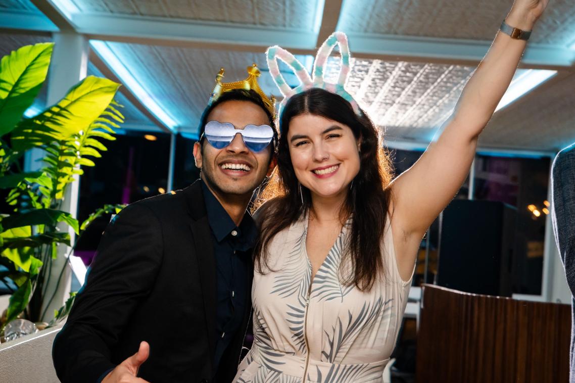 2 attendees wearing party prop crowns and sunglasses.